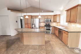 Kitchen with pendant lighting, a kitchen island, appliances with stainless steel finishes, and vaulted ceiling