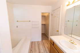 Bathroom featuring hardwood / wood-style floors, vanity, and a tub