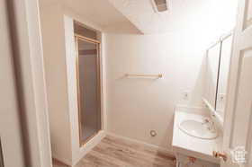 Bathroom featuring hardwood / wood-style floors, vanity, a textured ceiling, and a shower with door