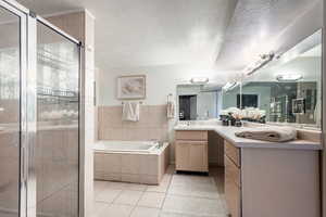 Bathroom featuring tile patterned floors, separate shower and tub, and a textured ceiling