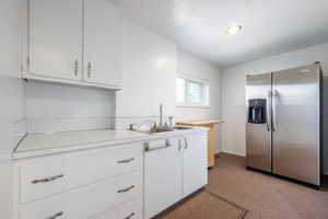 Kitchen featuring sink, white cabinetry, and stainless steel refrigerator with ice dispenser