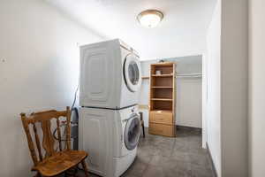 Laundry room featuring a textured ceiling and stacked washer / drying machine