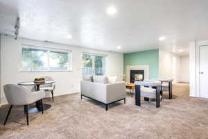 Living room with a fireplace, light colored carpet, and a textured ceiling