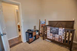 Carpeted bedroom featuring a crib