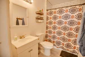 Bathroom featuring a shower with shower curtain, vanity, hardwood / wood-style flooring, and toilet