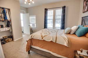 Bedroom with light carpet, cooling unit, and an inviting chandelier