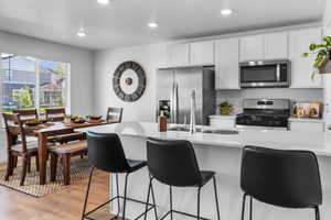 Kitchen with white cabinetry, stainless steel appliances, and light hardwood / wood-style floors