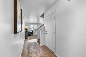 Hall with a textured ceiling and hardwood / wood-style flooring