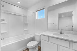 Full bathroom featuring toilet, vanity, wood-type flooring, and washtub / shower combination