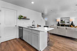 Kitchen with a breakfast bar, dark hardwood / wood-style flooring, kitchen peninsula, and sink