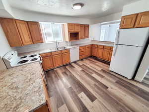 Kitchen with sink, , white appliances, decorative backsplash, and light wood-type flooring