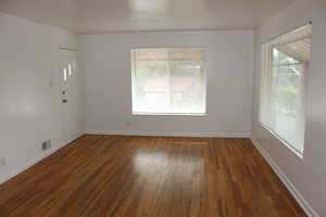 Unfurnished room featuring a healthy amount of sunlight and dark hardwood / wood-style flooring