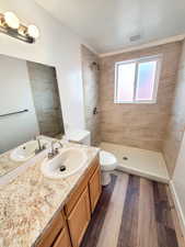 Bathroom featuring a tile shower, hardwood / wood-style floors, toilet, and vanity