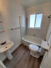 Bathroom with hardwood / wood-style flooring, shower / bathtub combination, and toilet