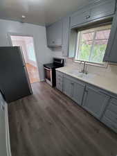 Kitchen with backsplash, sink, hardwood / wood-style floors, and stainless steel appliances