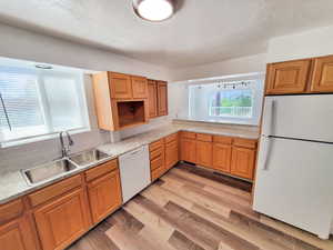 Kitchen featuring decorative backsplash,  white appliances, sink, and light hardwood / wood-style floors