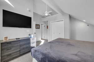 Carpeted bedroom with ceiling fan, a textured ceiling, high vaulted ceiling, and a closet