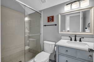 Bathroom with vanity, toilet, and a shower with shower door