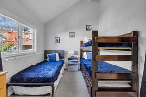 Carpeted bedroom featuring vaulted ceiling