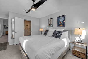 Carpeted bedroom featuring connected bathroom and ceiling fan