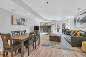 Living room with a brick fireplace, french doors, and light wood-type flooring