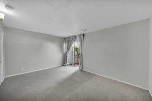 Carpeted empty room featuring a textured ceiling