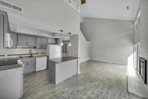 Kitchen featuring gray cabinetry, a center island, white appliances, high vaulted ceiling, and sink