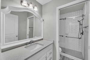 Bathroom featuring a tile shower, toilet, vanity, and hardwood / wood-style flooring