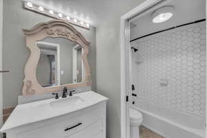 Full bathroom featuring tile patterned floors, vanity, a textured ceiling, toilet, and tiled shower / bath