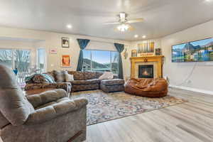Living room with plenty of natural light, ceiling fan, wood-type flooring, and a tile fireplace