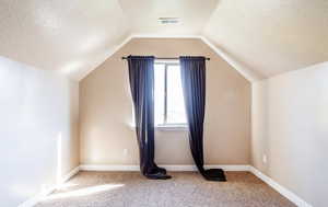Bedroom Two  featuring visible vents, a textured ceiling, carpet flooring, and vaulted ceiling