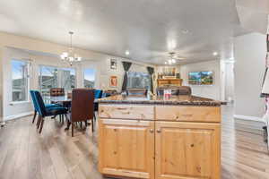 Kitchen with pendant lighting, a center island, ceiling fan with notable chandelier, light hardwood / wood-style flooring, and light brown cabinetry