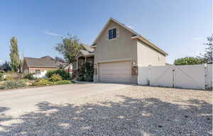 View of front of house featuring stucco siding, a gate, fence, concrete driveway, and a garage