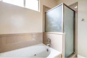Main level Primary bath featuring a stall shower and a garden tub