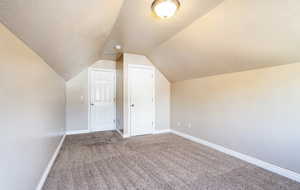 Bedroom Three room featuring baseboards, a textured ceiling, carpet, and vaulted ceiling