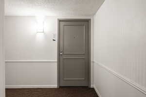 Doorway featuring carpet floors and a textured ceiling