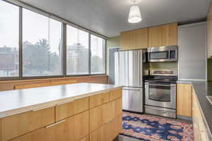 Kitchen with appliances with stainless steel finishes and pendant lighting