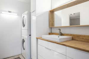 Laundry area featuring stacked washer / drying machine and sink