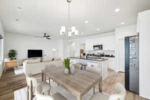 Dining area with ceiling fan with notable chandelier and light wood-type flooring