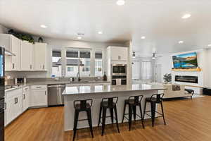 Kitchen with a kitchen bar, appliances with stainless steel finishes, white cabinets, and a kitchen island