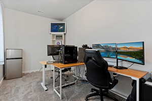 Carpeted home office featuring vaulted ceiling