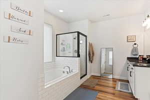 Bathroom with hardwood / wood-style flooring, vanity, and separate shower and tub