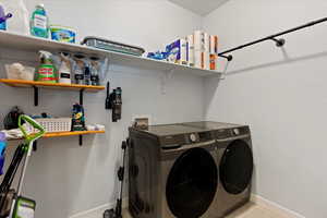 Laundry area featuring light tile patterned floors and washer and clothes dryer