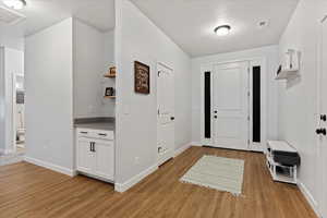 Foyer entrance with a textured ceiling and light hardwood / wood-style flooring