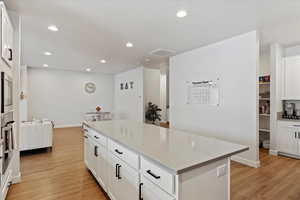 Kitchen with a center island, light hardwood / wood-style flooring, white cabinetry, and stainless steel microwave