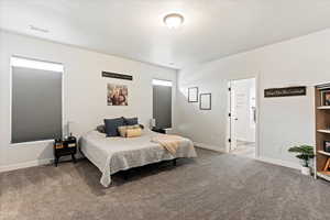 Bedroom featuring ensuite bathroom, carpet floors, and a textured ceiling