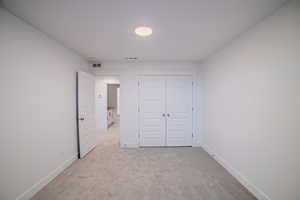 Unfurnished bedroom with baseboards, a closet, visible vents, and light colored carpet
