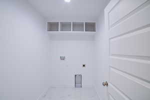 Clothes washing area with marble finish floor, laundry area, hookup for an electric dryer, baseboards, and hookup for a washing machine