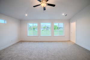 Spare room with carpet flooring, a wealth of natural light, baseboards, and lofted ceiling