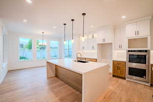 Kitchen featuring recessed lighting, double oven, light wood-style floors, and a sink